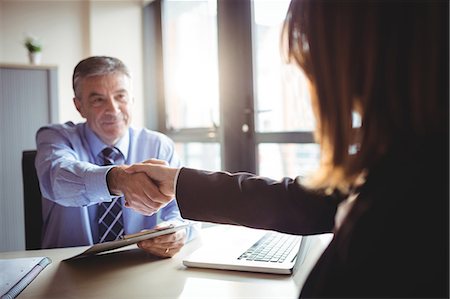 simsearch:6109-08690271,k - Businessman shaking hands with colleague in office Fotografie stock - Premium Royalty-Free, Codice: 6109-08701301