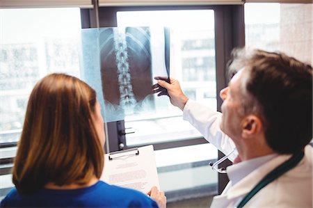 simsearch:400-05088220,k - Doctor examining x-ray while nurse writing on clipboard at the hospital Stock Photo - Premium Royalty-Free, Code: 6109-08701315
