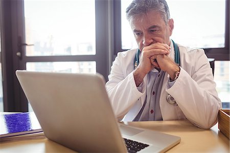 pensamiento - Doctor using laptop at his desk at the hospital Foto de stock - Sin royalties Premium, Código: 6109-08701334