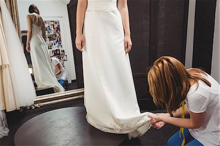 simsearch:6109-08701487,k - Woman trying on wedding dress in a studio with the assistance of creative designer Photographie de stock - Premium Libres de Droits, Code: 6109-08701490