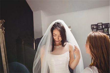 simsearch:6109-08701487,k - Woman trying on wedding dress in a studio with the assistance of creative designer Photographie de stock - Premium Libres de Droits, Code: 6109-08701492