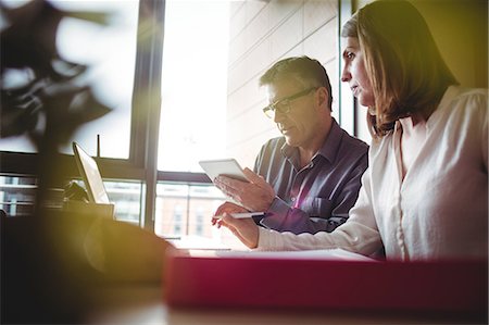 executive, chair - Man and woman discussing over digital tablet and laptop in the office Stock Photo - Premium Royalty-Free, Code: 6109-08701400