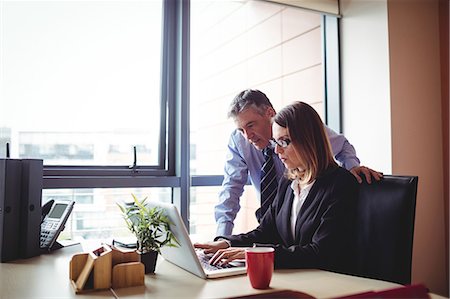 simsearch:6109-08765164,k - Businessman discussing with colleague over laptop in office Fotografie stock - Premium Royalty-Free, Codice: 6109-08701431