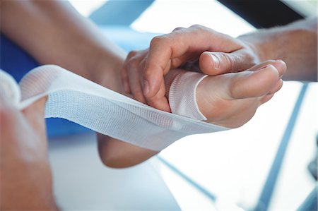 Male therapist putting bandage on female patient foot in clinic Foto de stock - Sin royalties Premium, Código: 6109-08701651