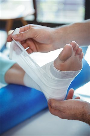 Male therapist putting bandage on female patient foot in clinic Photographie de stock - Premium Libres de Droits, Code: 6109-08701654