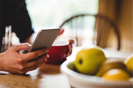 photos of hands and cups - Cropped image of woman using phone at home Photographie de stock - Premium Libres de Droits, Code: 6109-08705081