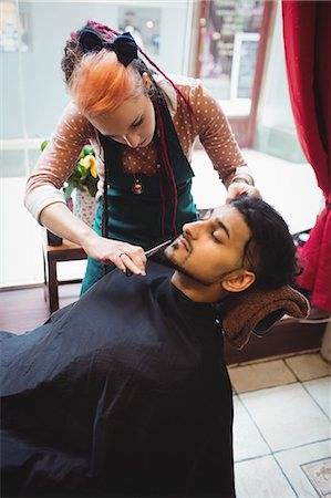 simsearch:6109-08705418,k - Man getting his beard trimmed with scissor in barber shop Foto de stock - Sin royalties Premium, Código: 6109-08705358