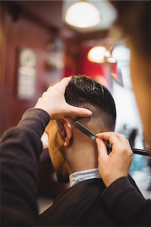 Man getting his hair trimmed with razor in barber shop Stock Photo - Premium Royalty-Free, Code: 6109-08705388