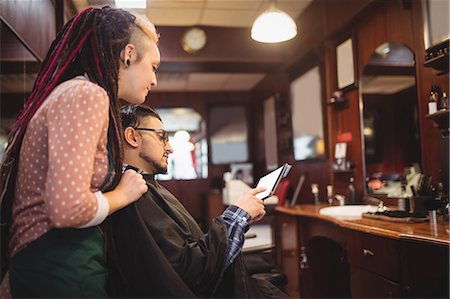 simsearch:6109-08705277,k - Client showing digital tablet to female barber in barber shop Foto de stock - Royalty Free Premium, Número: 6109-08705395