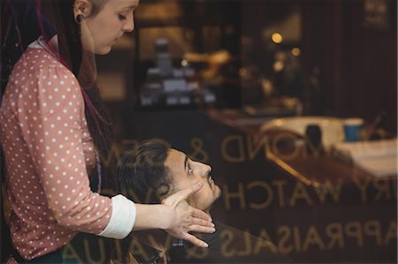 Man receiving a face massage from female barber in barber shop Stock Photo - Premium Royalty-Free, Code: 6109-08705398