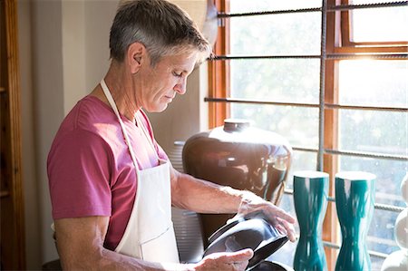 simsearch:6109-08705484,k - Male potter checking ceramic pot in pottery workshop Photographie de stock - Premium Libres de Droits, Code: 6109-08705465