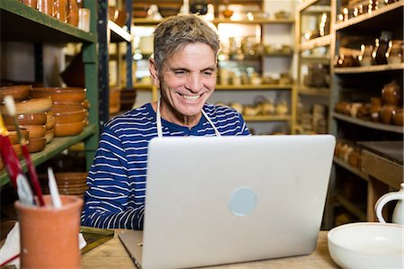 simsearch:6118-08660017,k - Happy male potter using laptop in pottery workshop Stock Photo - Premium Royalty-Free, Code: 6109-08705488