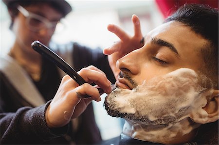 simsearch:6109-08705418,k - Man getting his beard shaved with razor in barber shop Foto de stock - Sin royalties Premium, Código: 6109-08705413