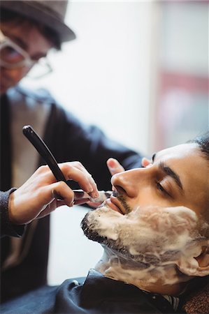 salon - Man getting his beard shaved with razor in barber shop Stock Photo - Premium Royalty-Free, Code: 6109-08705410