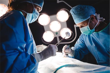 simsearch:6109-08829999,k - Surgeons performing operation in operation room at the hospital Foto de stock - Sin royalties Premium, Código: 6109-08720179