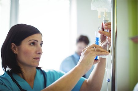 Nurse injecting medicine in infusion in hospital Photographie de stock - Premium Libres de Droits, Code: 6109-08720276