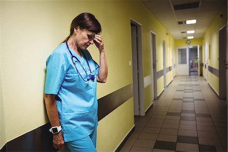 simsearch:6102-08951985,k - Depressed nurse standing in hospital corridor Foto de stock - Sin royalties Premium, Código: 6109-08720290