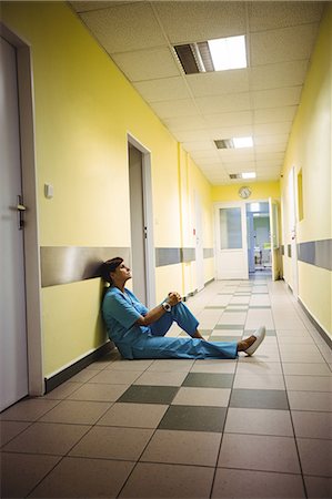 simsearch:6109-08720241,k - Depressed nurse standing in hospital corridor Stock Photo - Premium Royalty-Free, Code: 6109-08720294