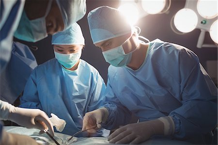 simsearch:6109-08830140,k - Surgeons performing operation in operation room at the hospital Foto de stock - Sin royalties Premium, Código: 6109-08720342