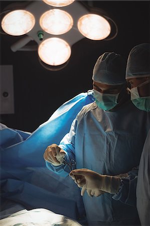 simsearch:6109-08830140,k - Surgeons performing operation in operation room at the hospital Foto de stock - Sin royalties Premium, Código: 6109-08720349