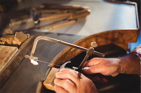 simsearch:6109-08720385,k - Close-up of goldsmith shaping metal with coping saw in workshop Photographie de stock - Premium Libres de Droits, Code: 6109-08720382