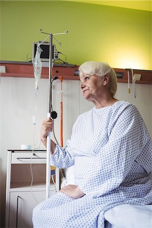 Thoughtful senior woman sitting on bed in hospital Foto de stock - Sin royalties Premium, Código: 6109-08720313