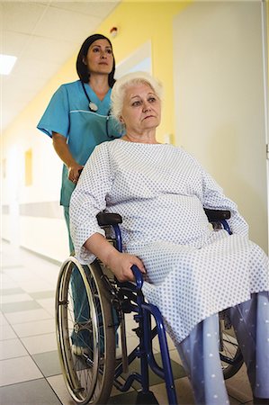 simsearch:6108-05860406,k - Nurse pushing a senior patient on a wheelchair in hospital Fotografie stock - Premium Royalty-Free, Codice: 6109-08720314