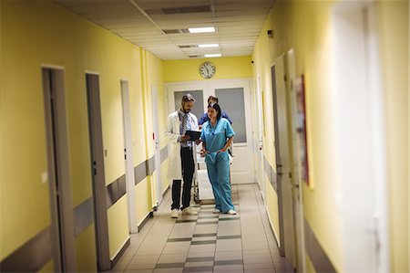 simsearch:6109-08689539,k - Male doctor and nurse interacting over a report in hospital corridor Stock Photo - Premium Royalty-Free, Code: 6109-08720333