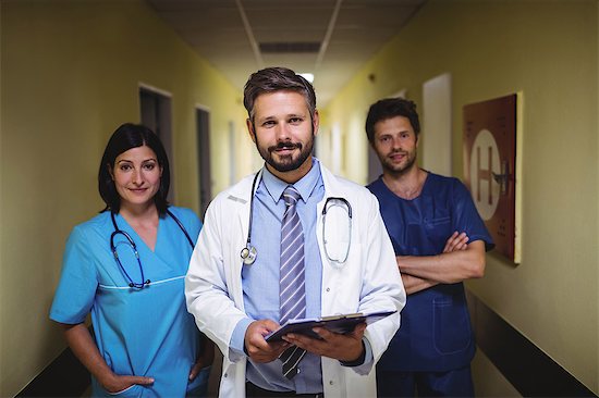 Portrait of doctor standing with nurse and ward boy in hospital corridor Stock Photo - Premium Royalty-Free, Image code: 6109-08720335