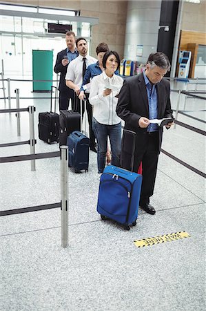 simsearch:400-03913175,k - Passengers waiting in queue at a check-in counter with luggage inside the airport terminal Foto de stock - Royalty Free Premium, Número: 6109-08722493