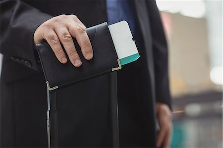 Mid section of passenger holding boarding pass and passport in airport terminal Photographie de stock - Premium Libres de Droits, Code: 6109-08722492