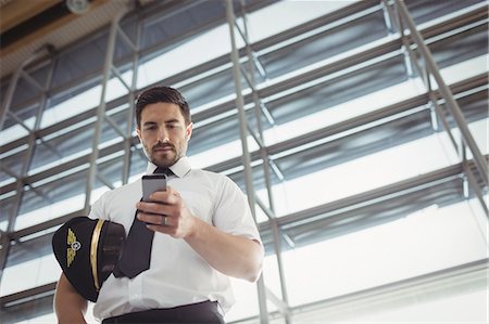 Pilot using mobile phone in waiting area at airport terminal Fotografie stock - Premium Royalty-Free, Codice: 6109-08722569