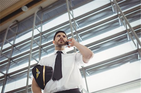 simsearch:693-06435879,k - Pilot talking on mobile phone in waiting area at airport terminal Photographie de stock - Premium Libres de Droits, Code: 6109-08722570