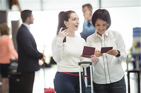 Two womens checking their passport in airport terminal Stock Photo - Premium Royalty-Free, Code: 6109-08722536