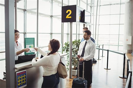Woman giving her passport to airline check-in attendant at airport check-in counter Stock Photo - Premium Royalty-Free, Code: 6109-08722657