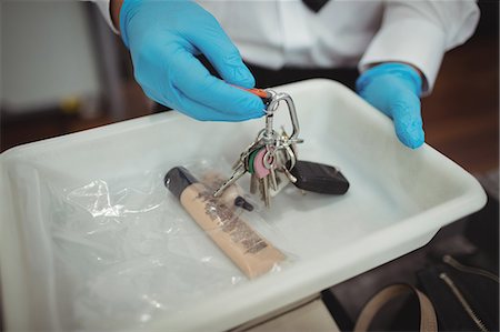 Security officer holding tray of liquid and key in airport Stock Photo - Premium Royalty-Free, Code: 6109-08722604