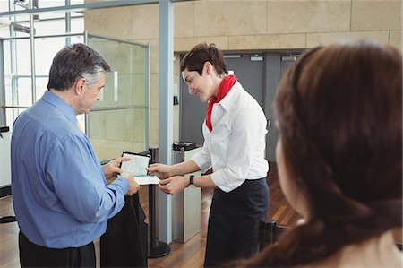 Businessman showing his boarding pass at the check-in counter in airport Foto de stock - Sin royalties Premium, Código: 6109-08722625
