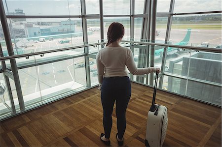 simsearch:6109-08929360,k - Rear view of businesswoman with luggage looking through glass window at airport Photographie de stock - Premium Libres de Droits, Code: 6109-08722633