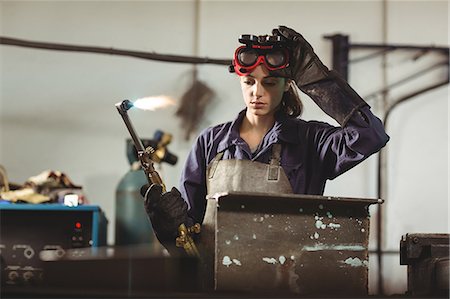 simsearch:6109-08722895,k - Female welder holding welding torch in workshop Stock Photo - Premium Royalty-Free, Code: 6109-08722796