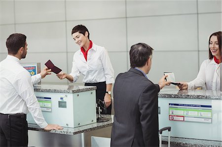 simsearch:6109-08802694,k - Airline check-in attendant handing passport to passenger at airport check-in counter Stock Photo - Premium Royalty-Free, Code: 6109-08722704