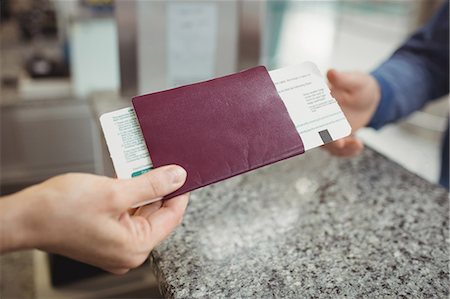 simsearch:6109-08929425,k - Airline check-in attendant handing passport to passenger at airport check-in counter Foto de stock - Sin royalties Premium, Código: 6109-08722718