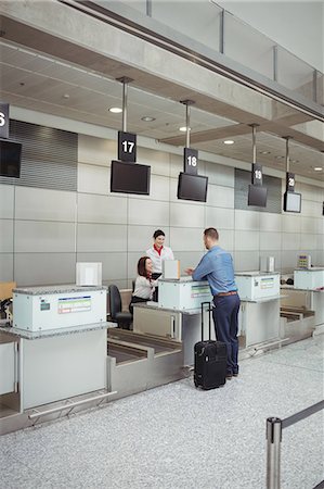 simsearch:6109-08929425,k - Airline check-in attendant handing passport to passenger at airport check-in counter Foto de stock - Sin royalties Premium, Código: 6109-08722727