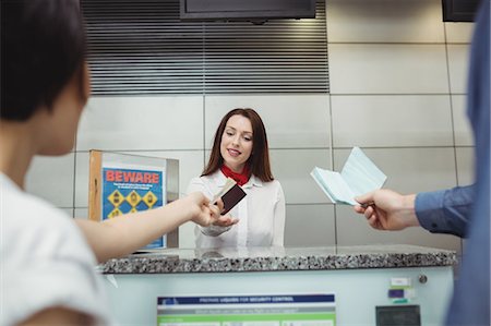 simsearch:6109-08929425,k - Passengers giving passport to airline check-in attendant at airport check-in counter Foto de stock - Sin royalties Premium, Código: 6109-08722732