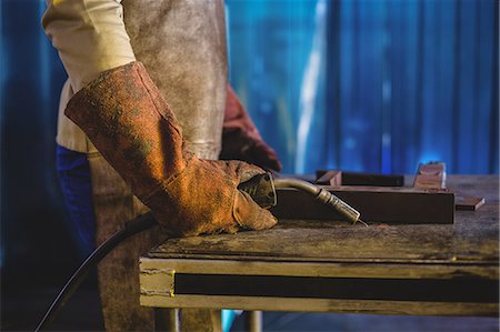 Mid-section of male welder holding welding torch in workshop Foto de stock - Sin royalties Premium, Código: 6109-08722840