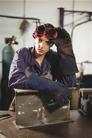 simsearch:6109-08722895,k - Portrait of female welder standing with a piece of metal in workshop Stock Photo - Premium Royalty-Free, Code: 6109-08722841