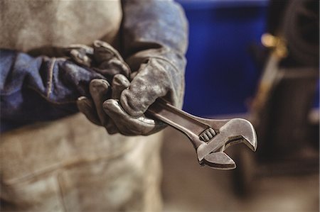 simsearch:6109-08722895,k - Mid-section of female welder holding wrench tool in workshop Stock Photo - Premium Royalty-Free, Code: 6109-08722846