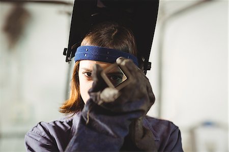 simsearch:6109-08722895,k - Female welder looking through a piece of metal in workshop Foto de stock - Sin royalties Premium, Código: 6109-08722854