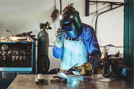 simsearch:6109-08722895,k - Female welder working on a piece of metal in workshop Foto de stock - Sin royalties Premium, Código: 6109-08722856