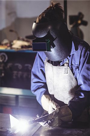 simsearch:6109-08722790,k - Female welder working on a piece of metal in workshop Foto de stock - Sin royalties Premium, Código: 6109-08722858