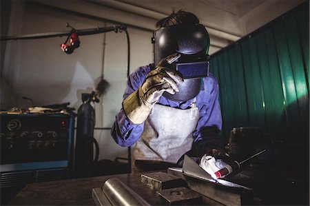 simsearch:6109-08722895,k - Female welder working on a piece of metal in workshop Stock Photo - Premium Royalty-Free, Code: 6109-08722860
